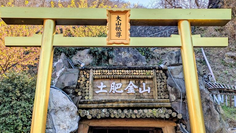 土肥金山の坑道入口。金色の鳥居の奥に「土肥金山」と彫られた扁額が掲げられ、その下に坑口が開いている
