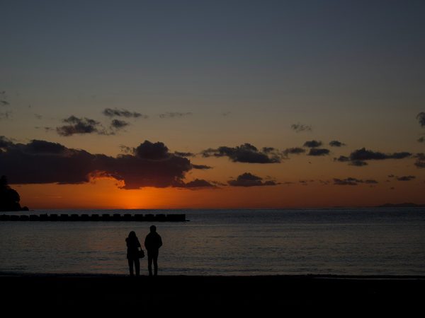 西伊豆・土肥の浜で、海に沈む夕日を眺めて立つ二人のシルエット