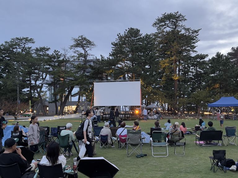 2025年の映画祭で、暮れかけた松原公園に椅子を並べてスクリーンを待つ来場者たち