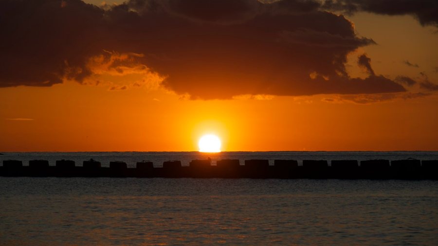 西伊豆・土肥の海に陽が沈むところ。堤防の向こうに大きな夕日が下りている